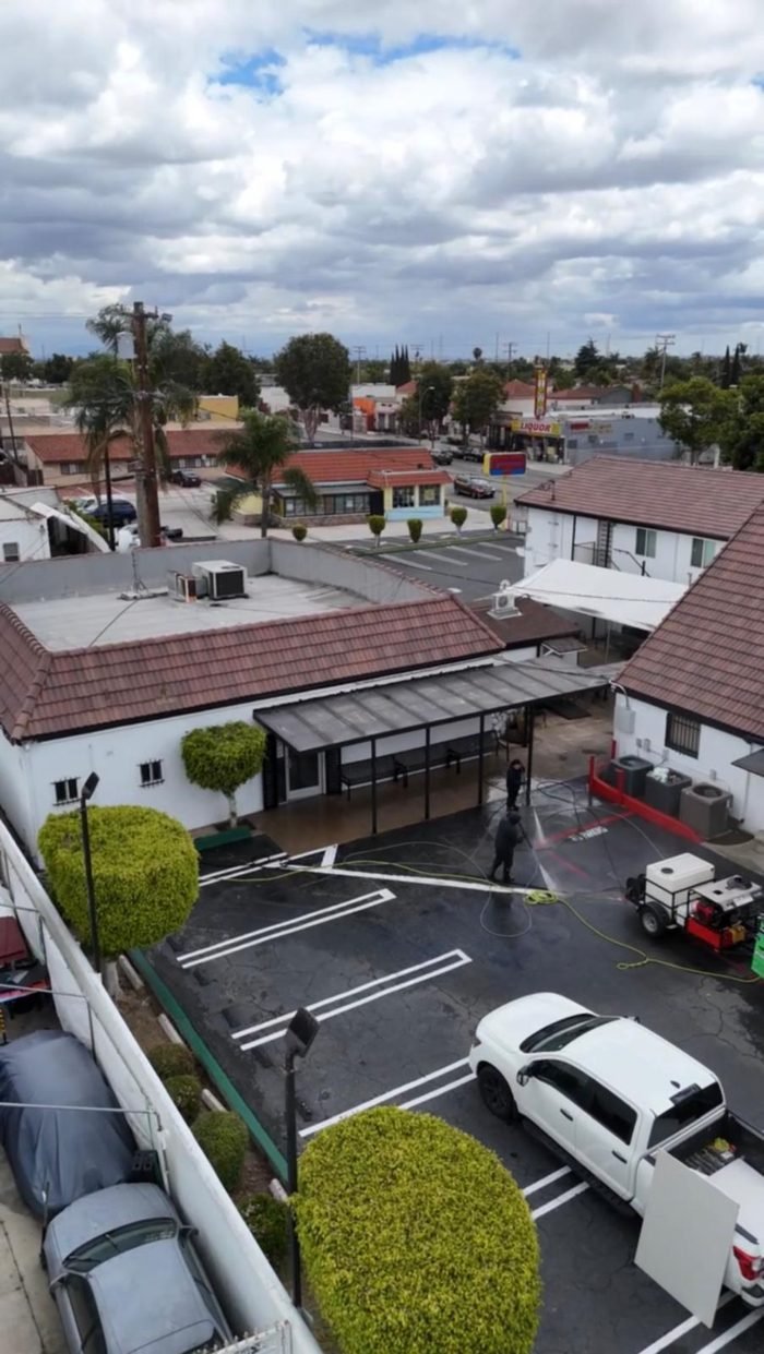 Elevated overview of a large commercial property while crews clean the parking area